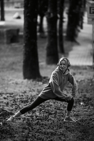 A woman wearing headphones is exercising outdoors. black and white photo.の写真素材