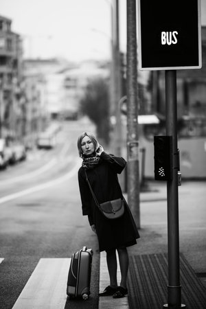 A woman is walking on the street with a suitcase. Black and white photo.の写真素材