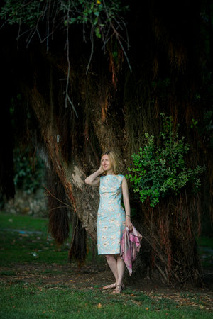 A woman is standing by a large tree in a park.の写真素材