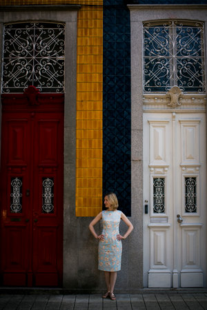 A woman stands in front of a traditional house with high doors in Porto, Portugal.の写真素材