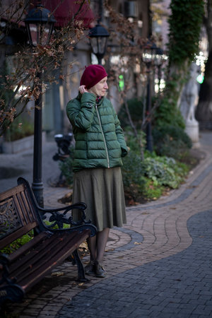 A woman in fall clothes near a bench in the park.の写真素材