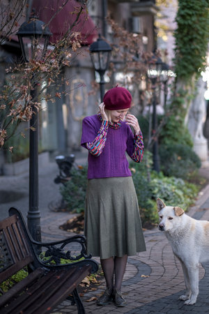 A woman is standing with a stray dog.の写真素材