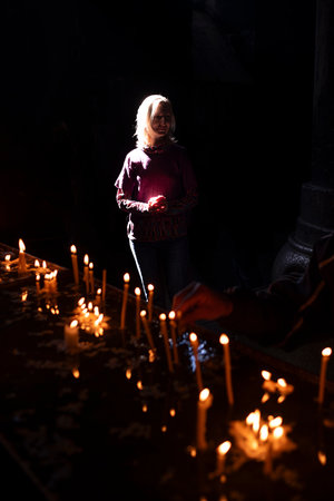 A woman stands in the temple near burning candles.の写真素材
