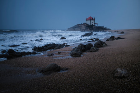 View of Chapel of Senhor da Pedra on Miramar Beach in rainy weather at dusk. Portugal.の写真素材