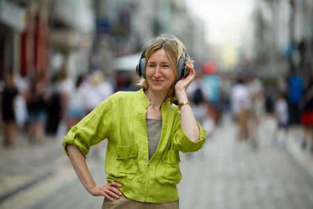 A woman enjoying music on headphones on a busy street.の写真素材