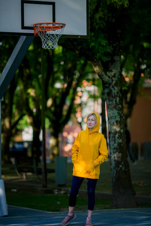 A woman wearing a hoodie stands on a basketball court.の写真素材
