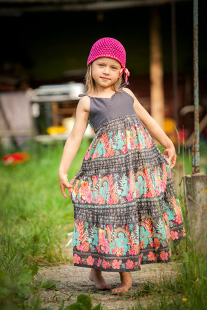 A little girl in a dress poses for the camera in the countryside.の写真素材
