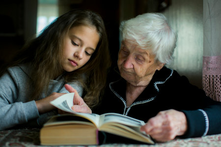A grandmother reads a book with her preschool granddaughter.