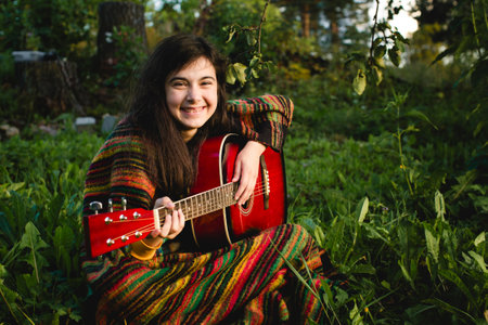 A girl playing guitar in the garden.の写真素材