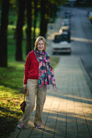 A portrait of a middle-aged woman on a pathway, exuding confidence and grace amidst the surroundings.の写真素材