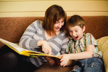 A woman reading a book with her young son.の写真素材