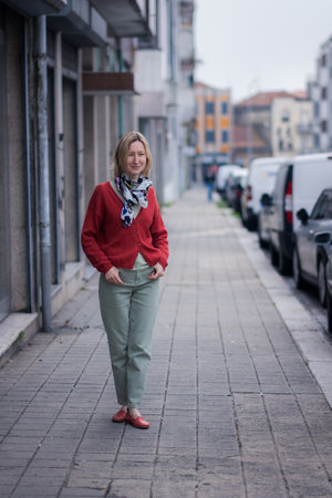 A stylish woman in a blouse and jeans stands alone on an empty street.の写真素材