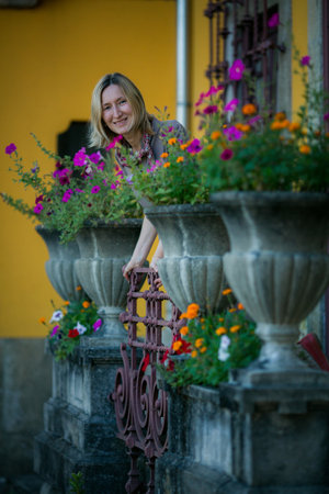 A woman smiles while looking at the camera, standing between old stone flower pots at a Portuguese villa.の写真素材