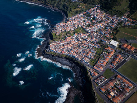 Aerial view of the coastal village of Maia in Ribeira Grande, Azores, with traditional white houses nestled between lush green hills and the Atlantic Ocean.の写真素材