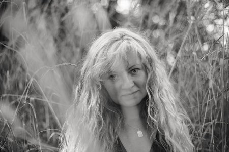 A black-and-white portrait of a woman with Slavic features and straw-colored hair, standing amidst tall grass in an open field, blending elegance withnature's raw beauty.の写真素材