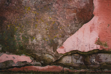 A textured wall with crumbling plaster and dampness, showing the effects of age and wear.の写真素材