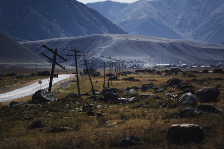 A road through the mountains of the Altai Republic, surrounded by boulders and power line poles along the way.の写真素材