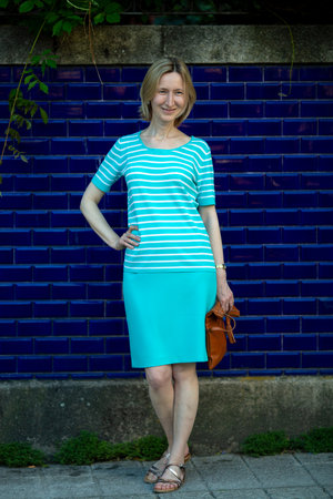 A woman in a cheerful summer mood stands near an outdoor wall covered with blue tiles, embracing the vibrant Portuguese atmosphere.の写真素材