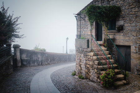 Stone houses in Monsanto, Portugal, shrouded in mist on a foggy autumn day, creating a mystical and atmospheric scene.の写真素材