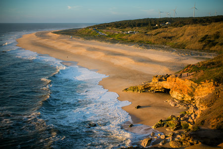 Atlantic beach with gentle waves in Nazare, Portugal, on a calm and peaceful day.の写真素材