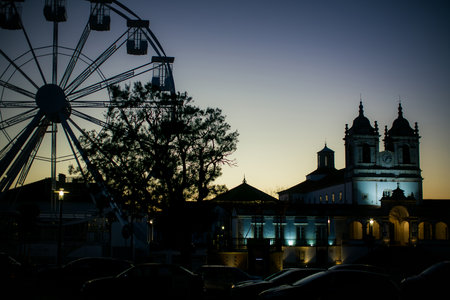 Silhouettes of a temple and a Ferris wheel at twilight in NazarÃ©, Portugal.の写真素材