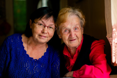 A warm, family portrait of a middle-aged woman posing with her elderly mother, radiating love and connection.の写真素材