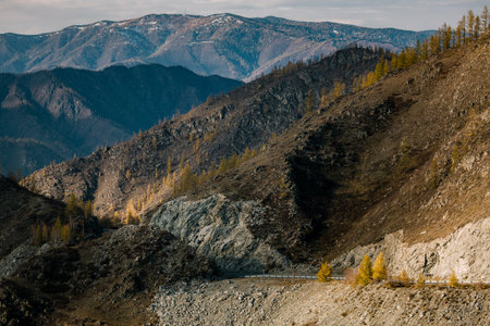 A solitary road winds through the harsh, imposing mountains of the Altai Republic. The dramatic landscape is raw and powerful, shaped by time, wind, and silence.の写真素材