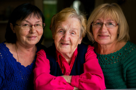 A touching portrait of an elderly woman with her two middle-aged daughters. Their faces reflect warmth, shared history, and the quiet strength of a lifelong bond.の写真素材