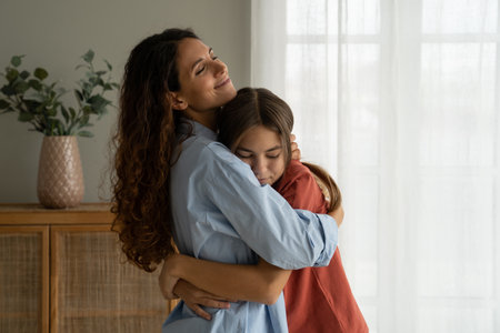 Young loving mother hugging teenage daughter at home, mom cuddling supporting upset teen girlの写真素材