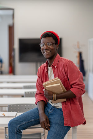 Happy smiling African guy university student in classroom or libraryの写真素材