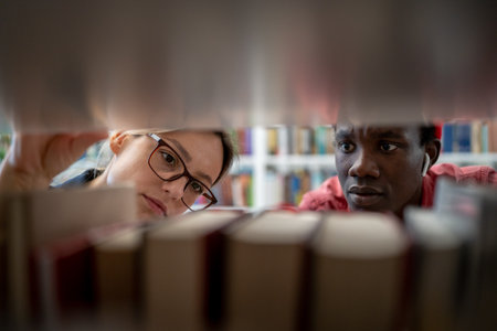 Two diverse students searching sources for research project in university libraryの写真素材