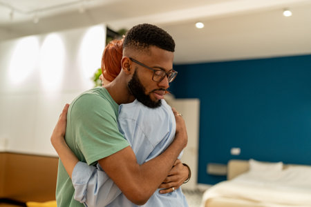 Young diverse couple man and woman making peace after quarrel fight at home, hugging embracing.の写真素材