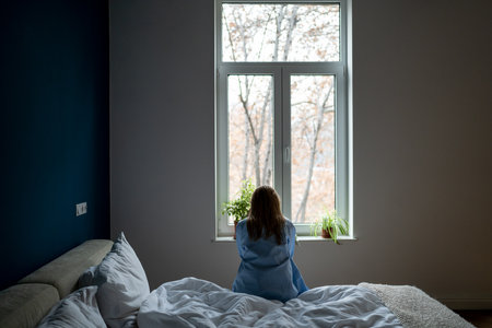 Alone woman sit on bed at home pondering solution trouble, suffer from breakup, divorce, feel unwellの写真素材