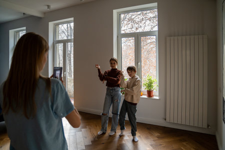 Mother holding smartphone helping kids to record funny dance video for social media