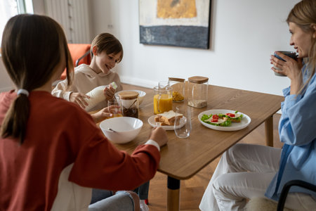 Happy family having breakfast while sitting at kitchen tableの写真素材