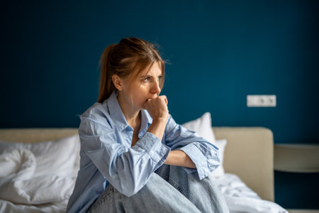 Depressed stressed middle age woman sit biting fingers with nervous breakdown after emotional traumaの写真素材