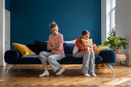 Upset frustrated mother and teenage daughter ignoring each other after quarrel at home, not talkingの写真素材