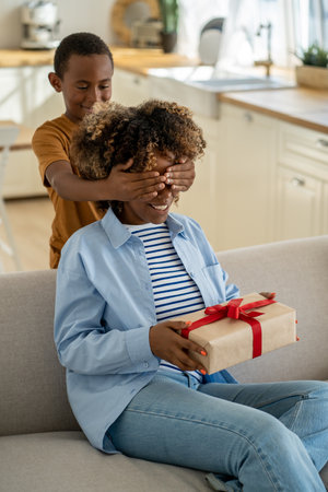 Excited happy African American woman mother receiving mothers day gift from childの写真素材