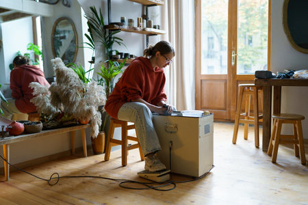 Creative woman sit in cozy ceramic studio workshop uses learning operate pedal potter wheel for clayの写真素材
