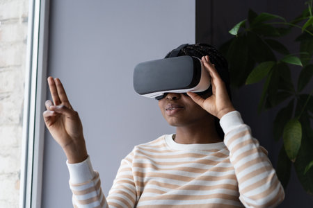 African woman wearing VR helmet touching air with finger, testing modern hi-tech future gadgetの写真素材
