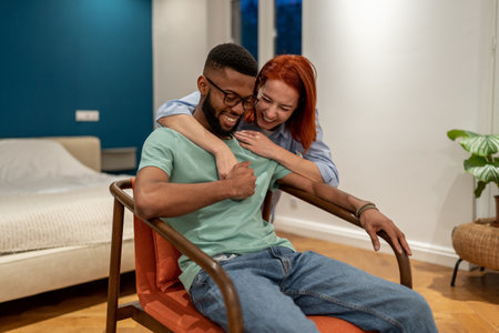 Happy interracial young couple laughing together, bonding at homeの写真素材