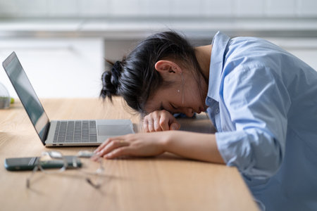 Work burnout. Tired asian woman putting head down on table, suffering from chronic job stress.の写真素材