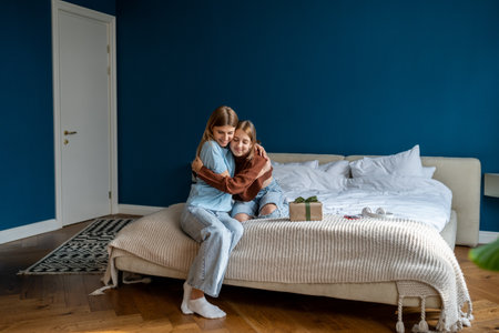 European loving family mom and girl cuddling, thanks for present gift enjoying time together at homeの写真素材