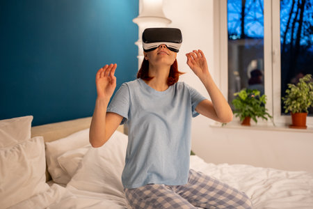 Young woman using virtual reality glasses on bed. Girl plays video games in simulator helmet
