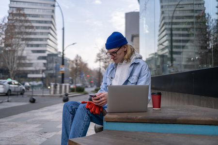 Hipster guy freelancer with smartphone and laptop outdoorsの写真素材