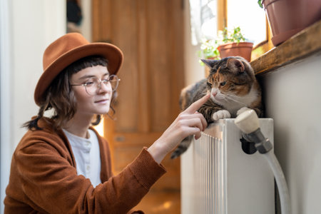 Happy smiling teen girl playing with cat at homeの写真素材