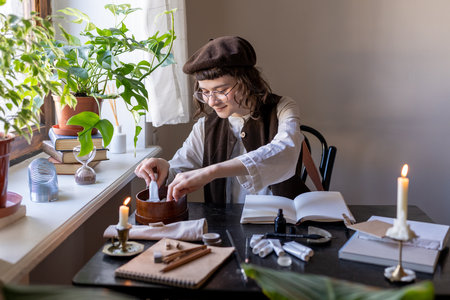 Smiling millennial girl artist wearing beret choosing paints while creating art in cozy art studio