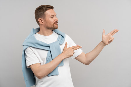 Optimistic confident man promoter points with two hands shooting to right on free space backgroundの写真素材