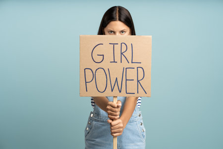 Teenage girl holding banner girl power slogan isolated on studio blue backgroundの写真素材