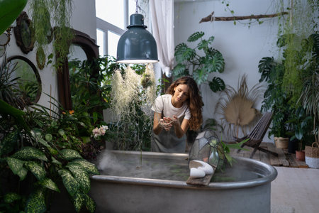 Girl gardener taking care about aquatic plant in greenhouse holding houseplant under bath with waterの写真素材